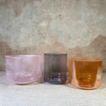 Load image into Gallery viewer, Three crystal sound bowls in pink, purple, and orange on a textured surface with a neutral background.