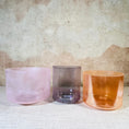 Load image into Gallery viewer, Three crystal sound bowls in pink, purple, and orange on a textured surface.