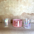 Load image into Gallery viewer, Three crystal sound bowls with iridescent and pink finishes on a textured surface.