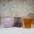 Load image into Gallery viewer, Three crystal sound bowl in pink, purple, and amber on a textured surface with a neutral background.
