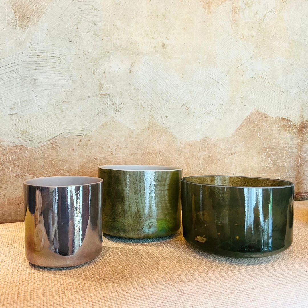 Three crystal sound bowls of different sizes on a textured surface