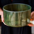 Load image into Gallery viewer, Person holding a green crystal sound bowl with a blurred background
