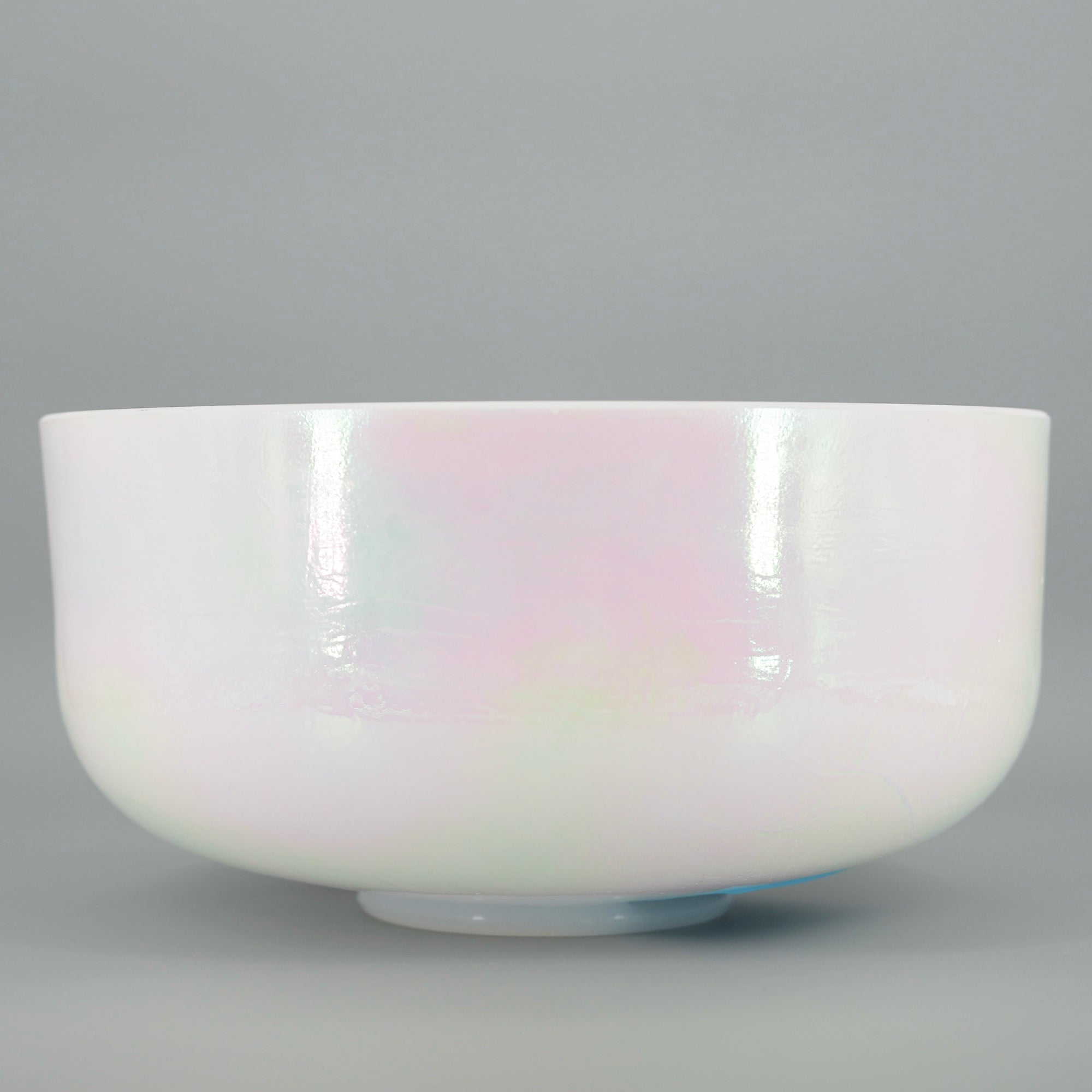 Pearl white crystal sound bowl with iridescent finish on a gray background