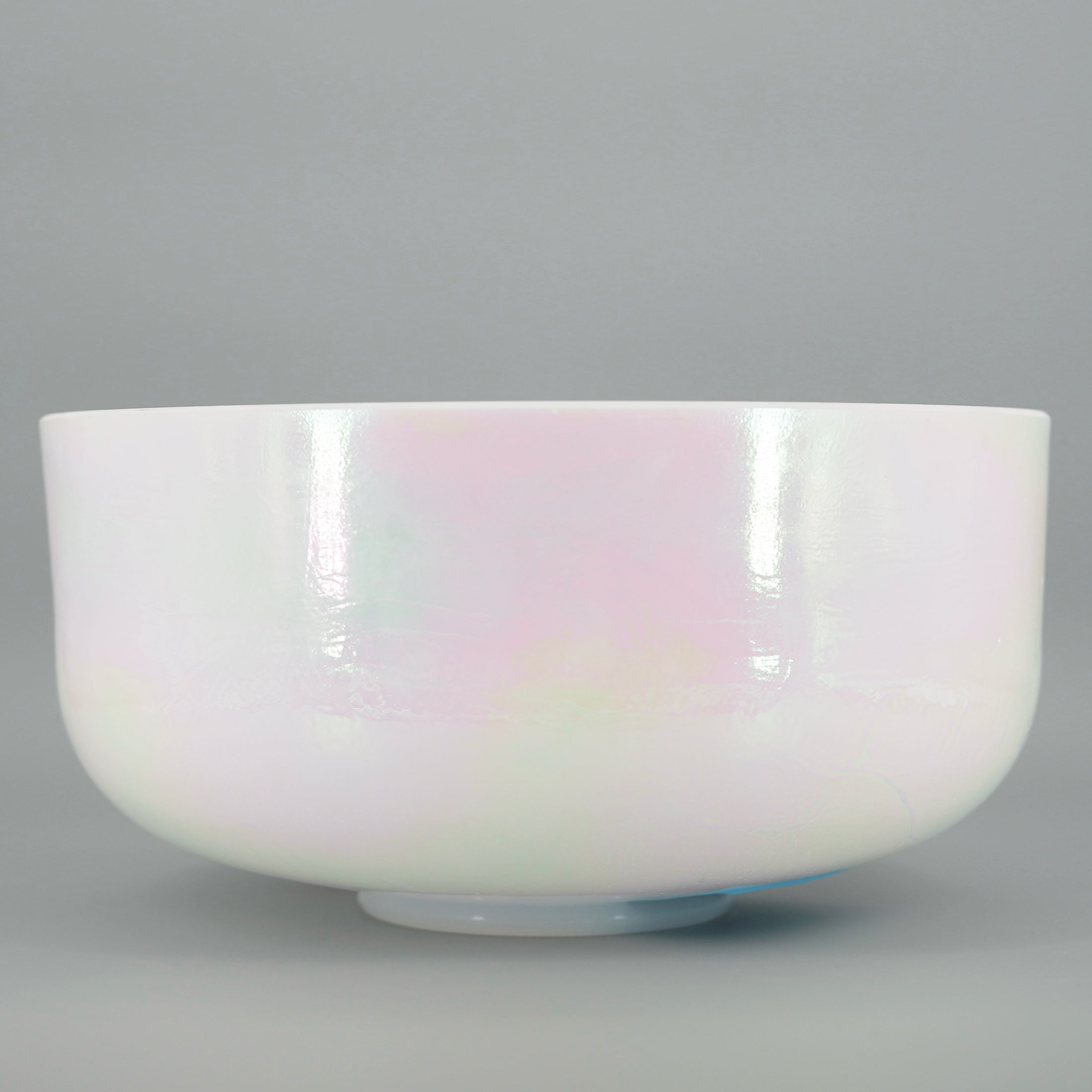 Pearl white crystal sound bowl with iridescent finish on a gray background