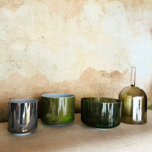 Set of four cystal sound bowls in different colours on a textured surface with a neutral background