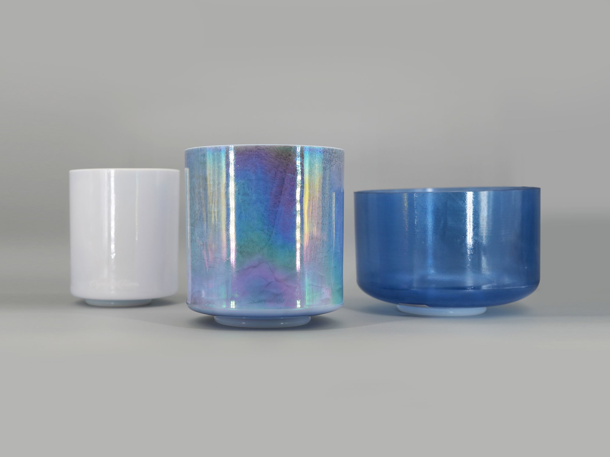 Three crystal sound bowl with reflective surfaces on a gray background