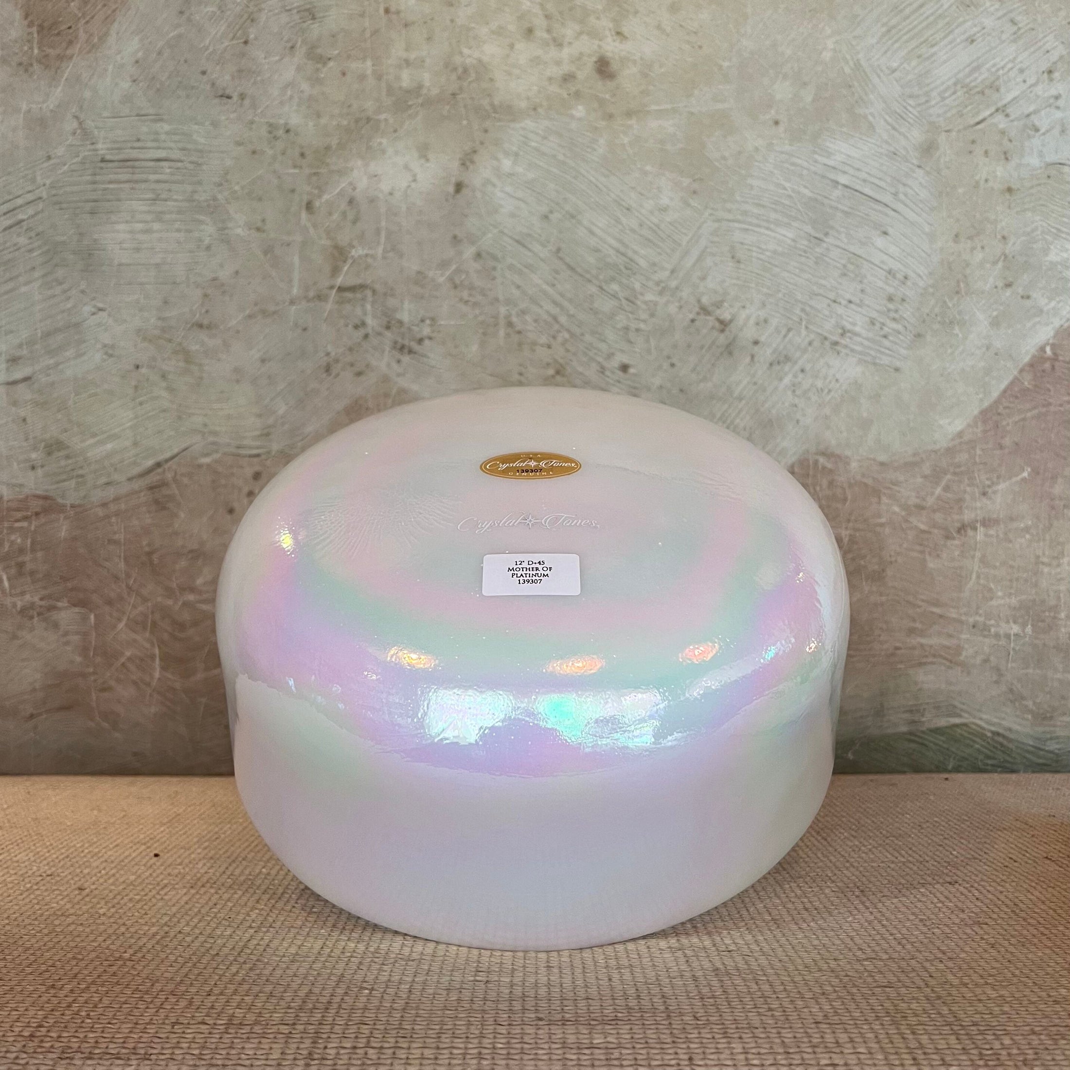 Iridescent crystal sound bowl with a Crystal Tones label on a textured surface