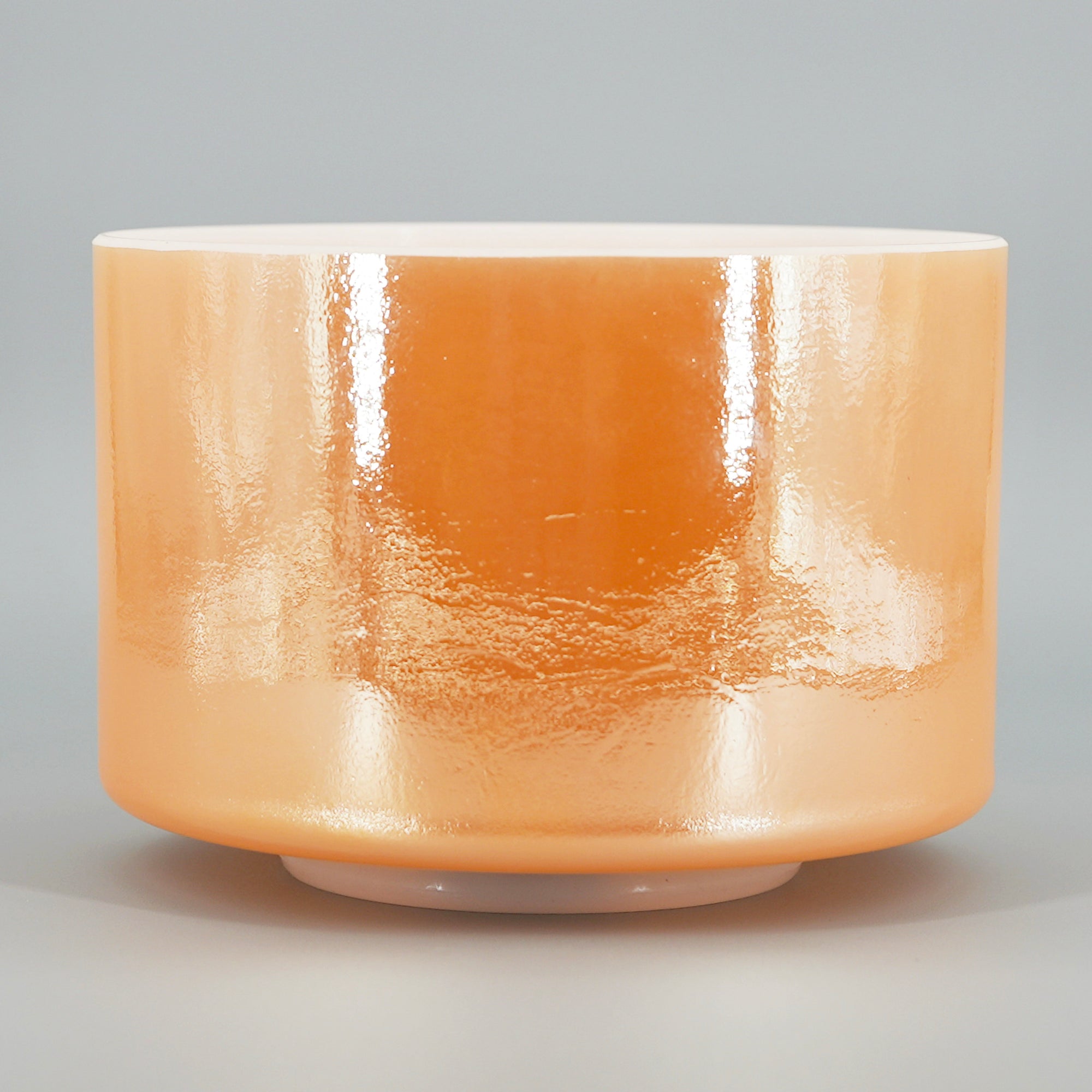 Orange Crystal sound bowl with a glossy finish on a gray background