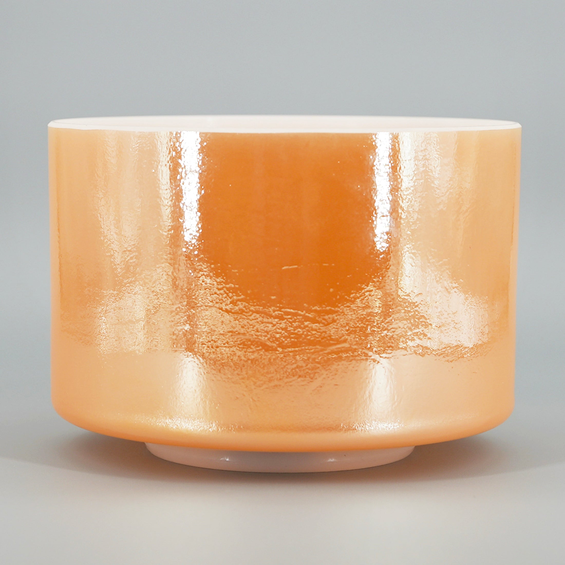 Orange Crystal sound bowl with a glossy finish on a gray background