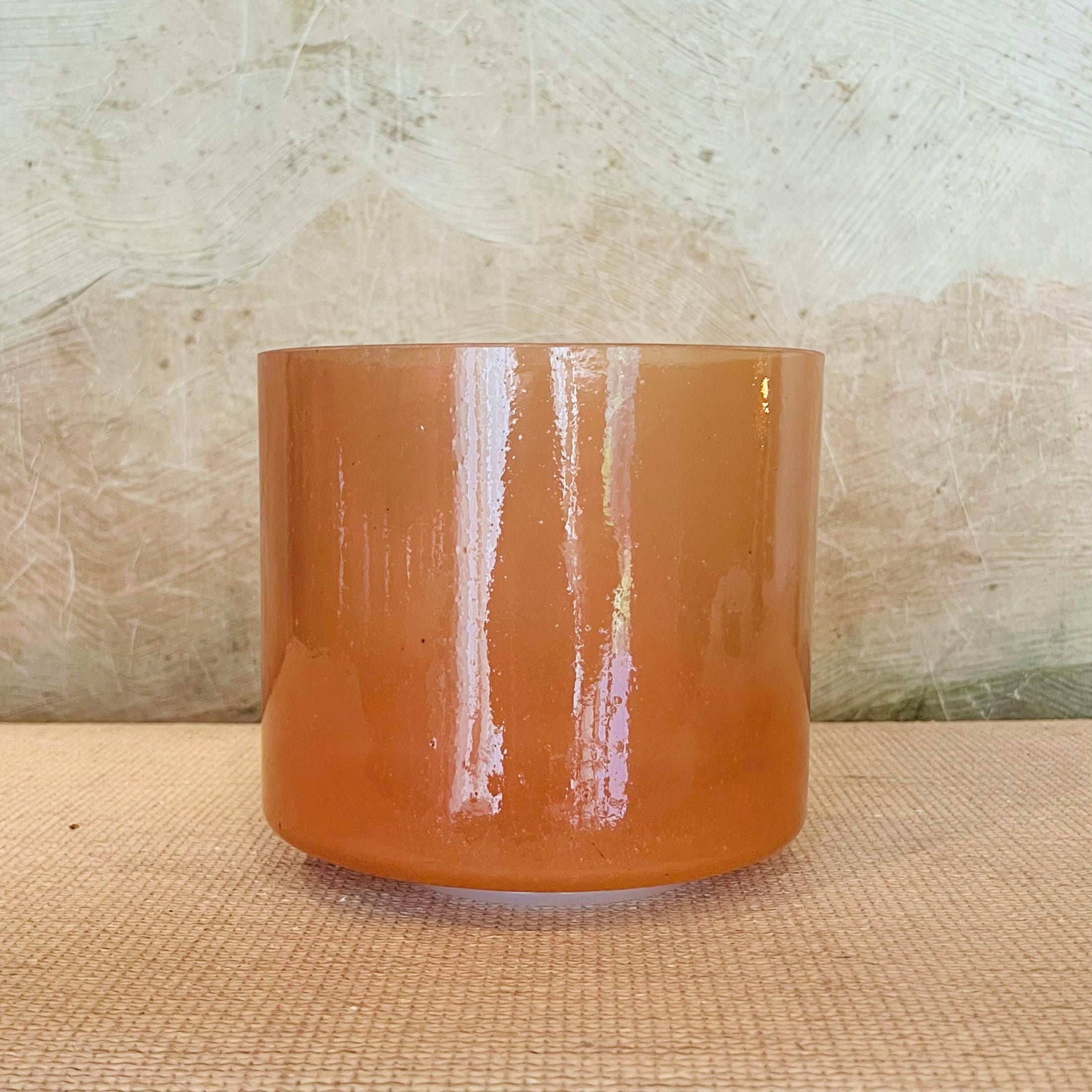 Orange crystal sound bowl on a textured surface with a neutral background