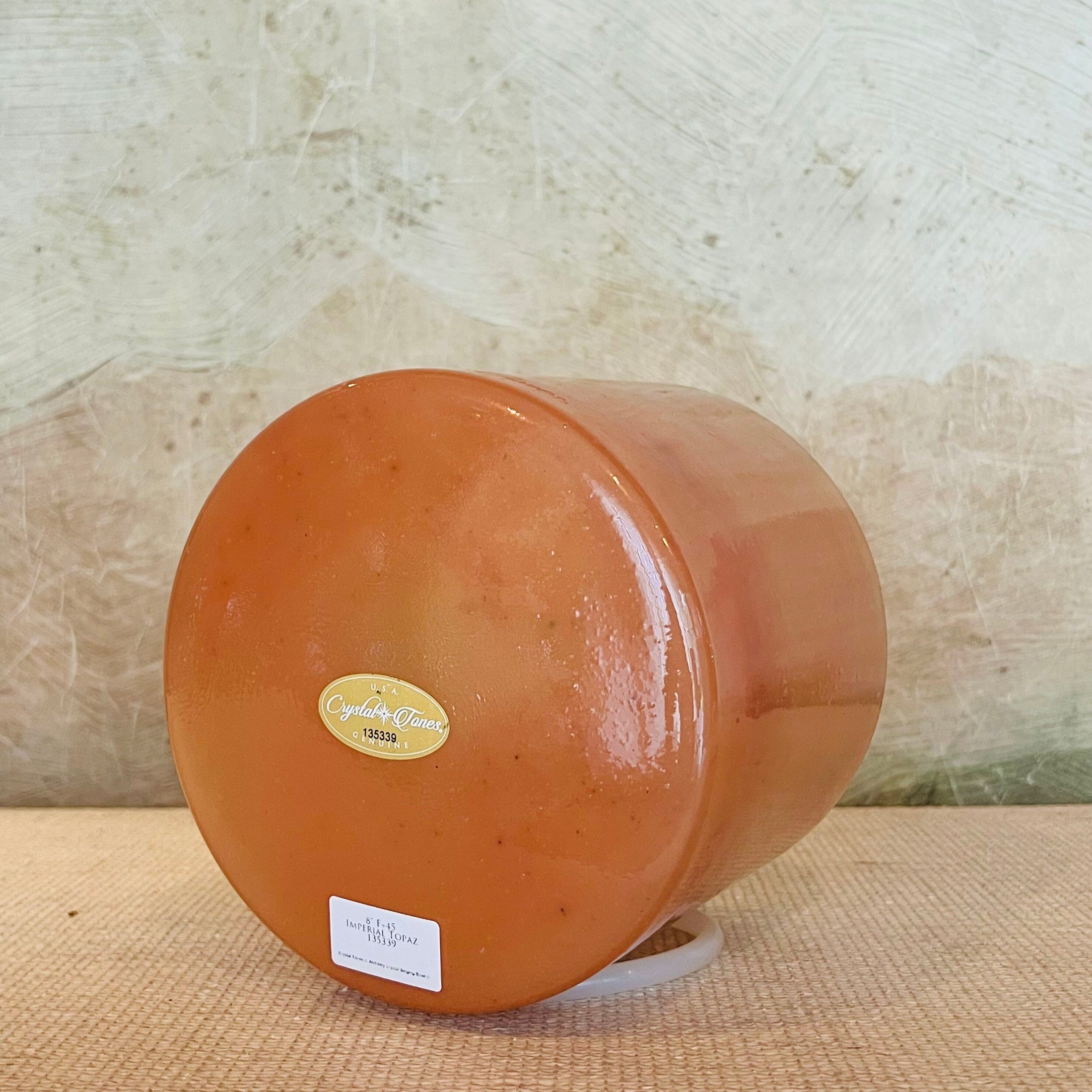 Round terracotta-colored crystal sound bowl with a visible Crystal Tones brand label on a textured surface.
