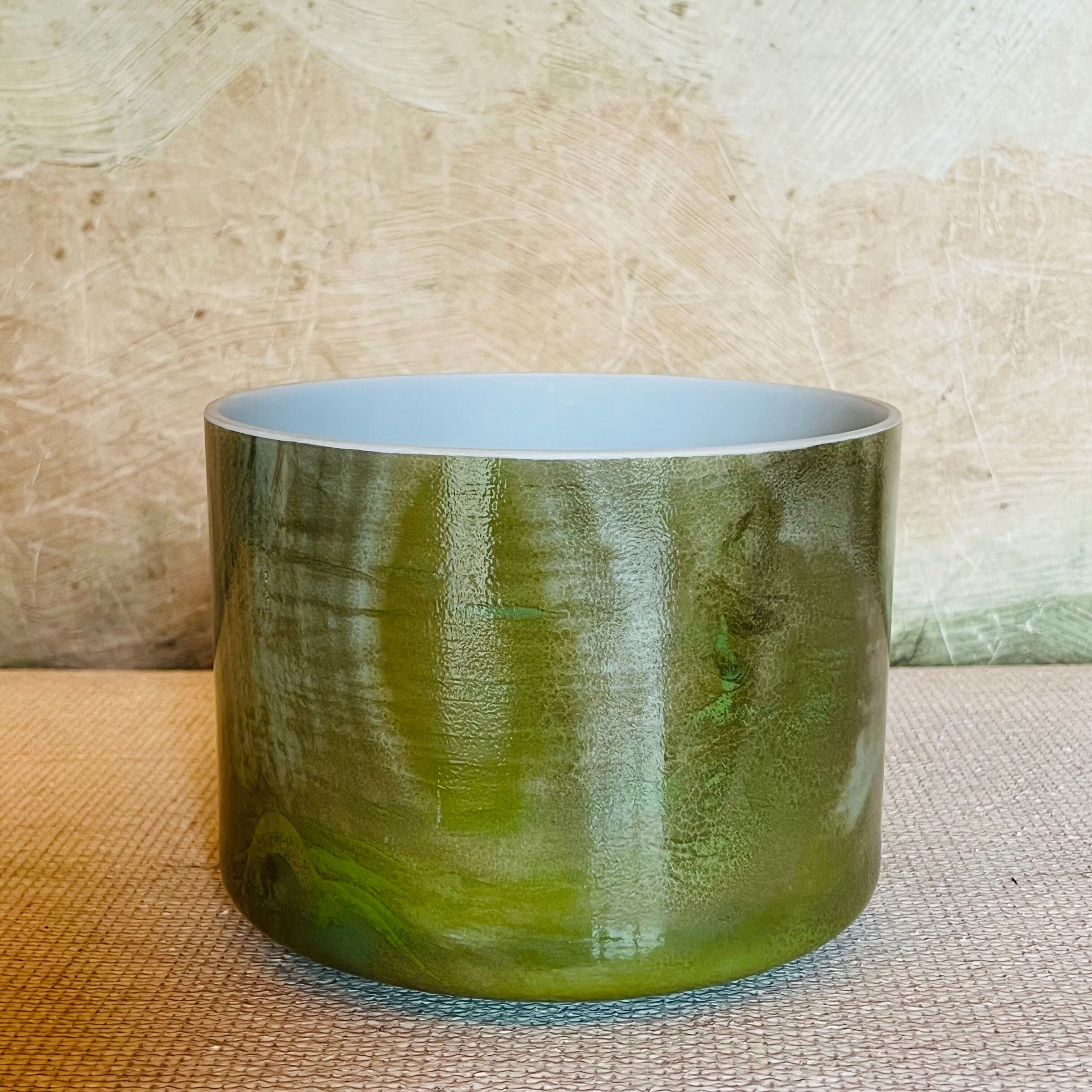 Green Crystal Sound Bowl on a textured surface with a neutral background