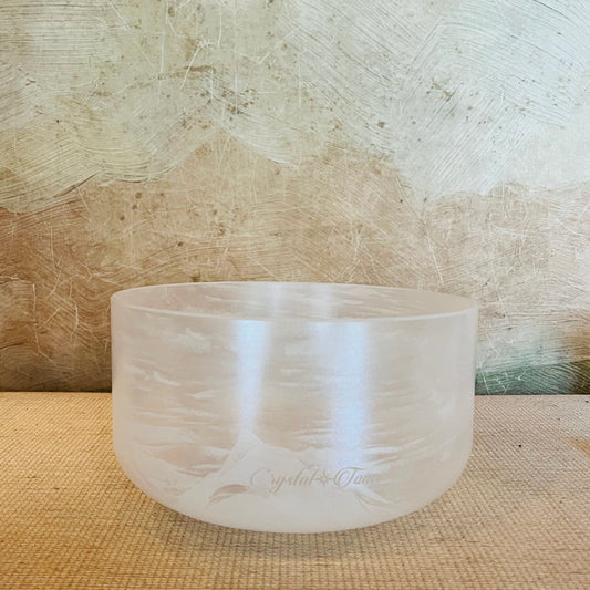 Clear crystal singing bowl on a textured surface with a neutral background