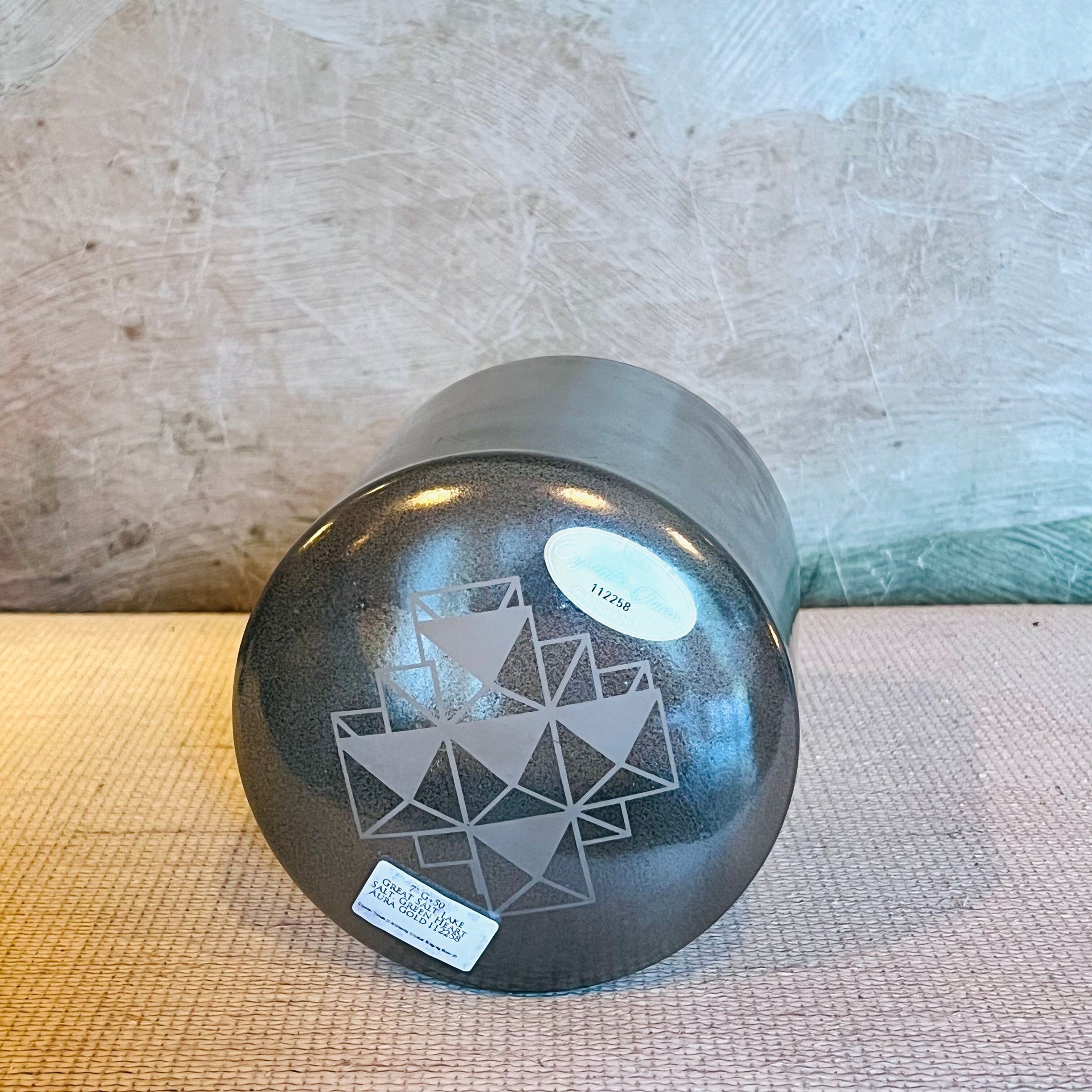 Black crystal sound bowl with geometric design on a textured surface