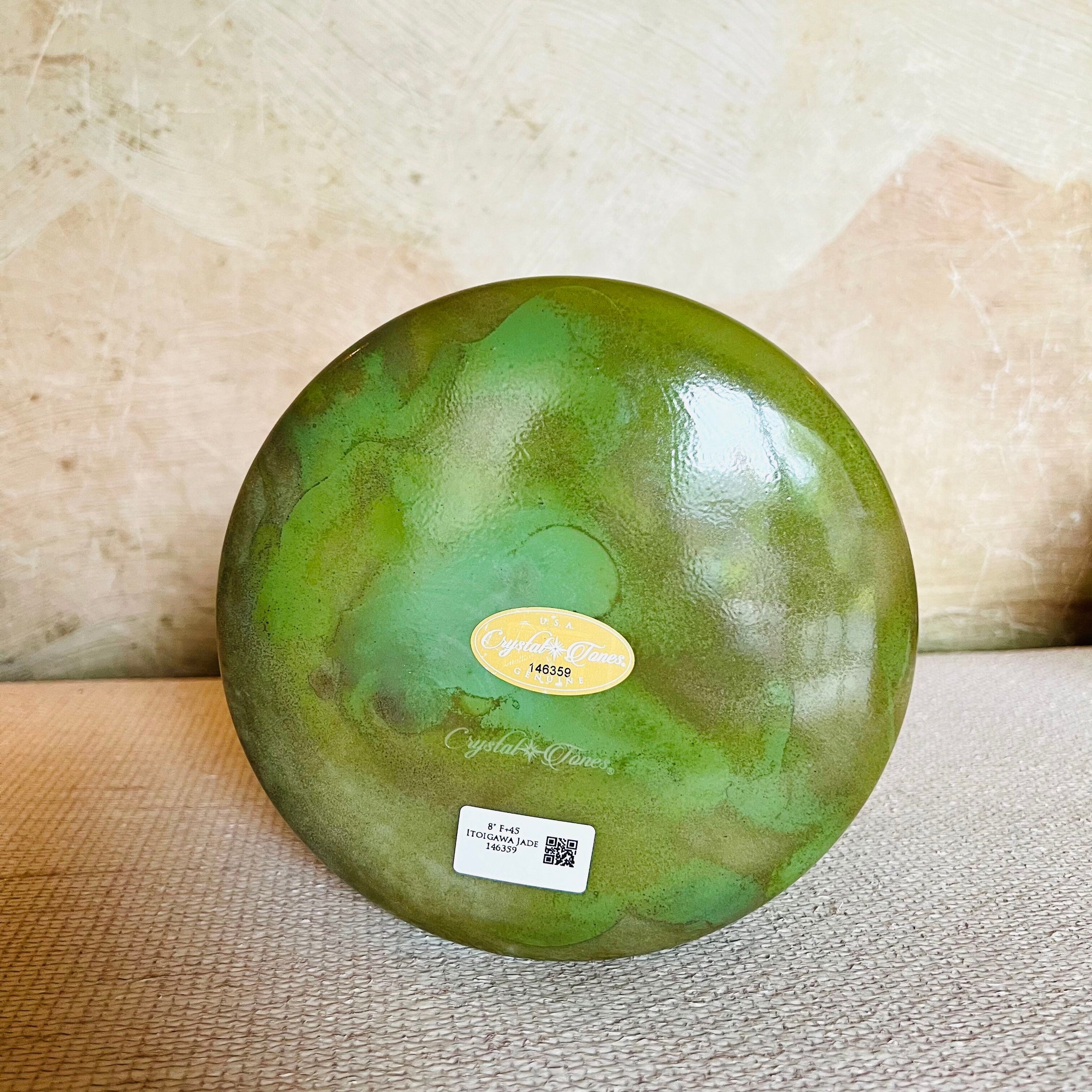 Green Crystal Sound Bowl with a Crystal Tones label on a textured surface