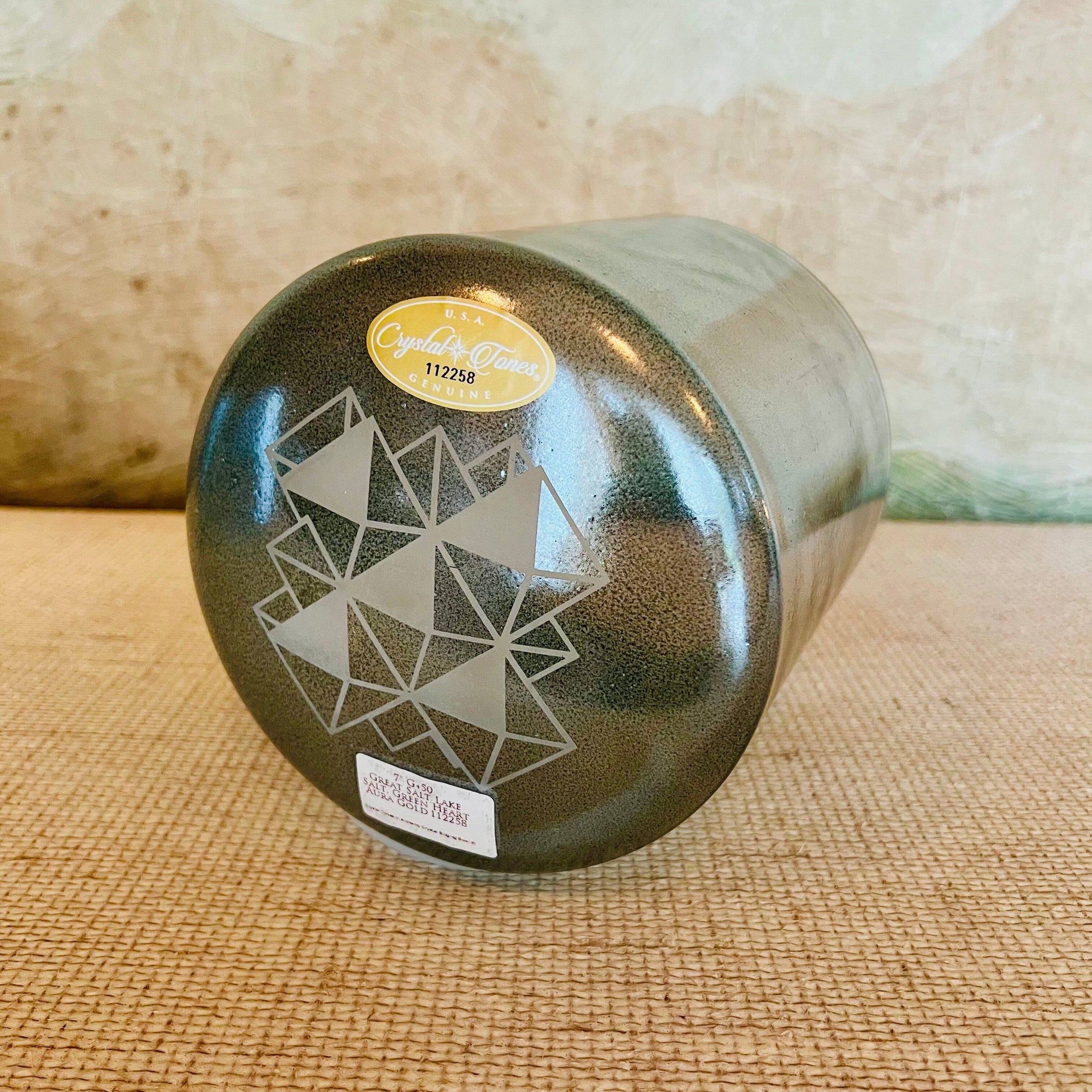 Green crystal sound bowl with geometric design on a woven surface