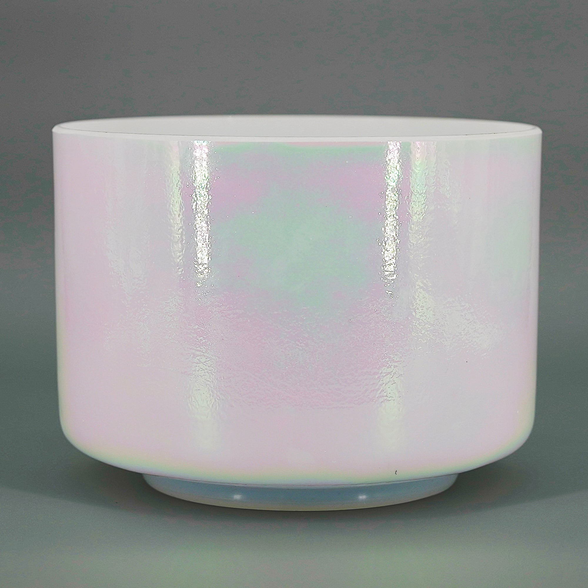 Cylindrical crystal sound bowl with a pastel, iridescent glaze on a gray background
