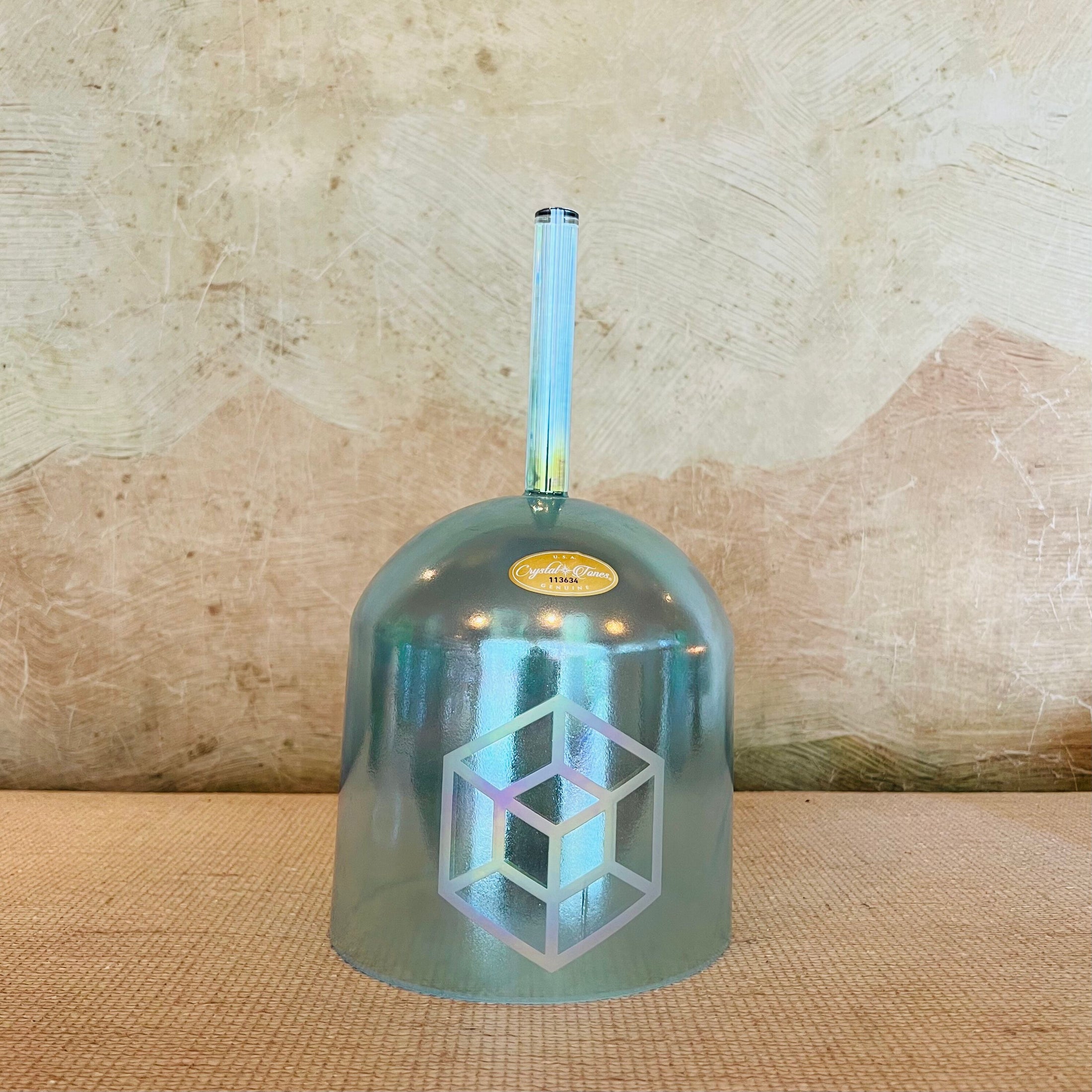 Metallic blue crystal sound bowl with geometric design on a textured surface