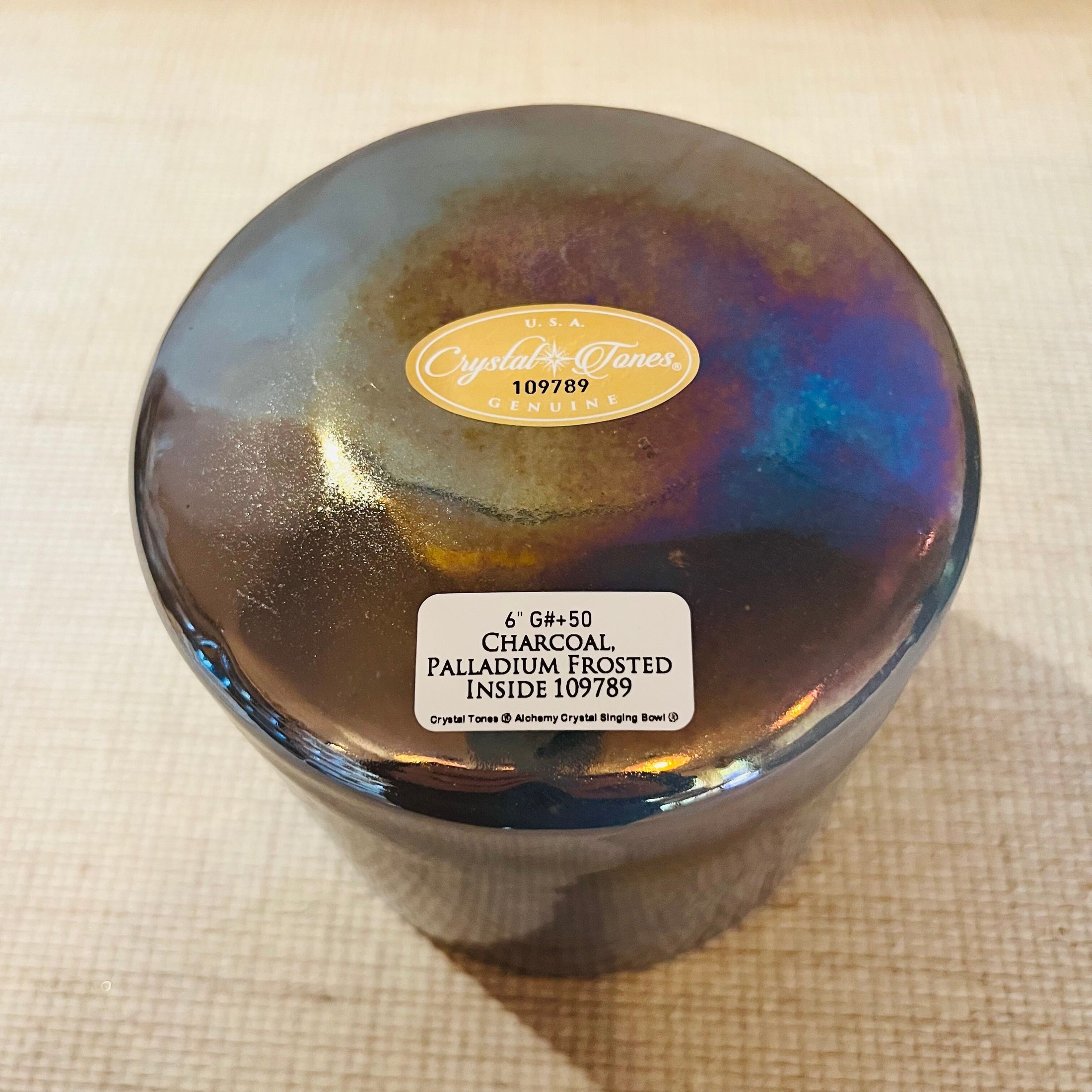 Iridescent Crystal Sound Bowl with a Crystal Tones label on a textured beige surface