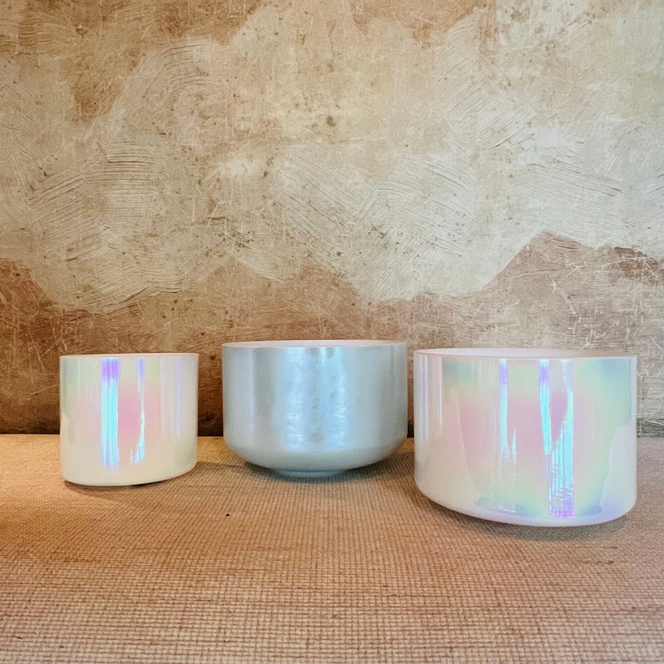 Three iridescent Crystal Sound Bowl on a textured surface with a neutral background