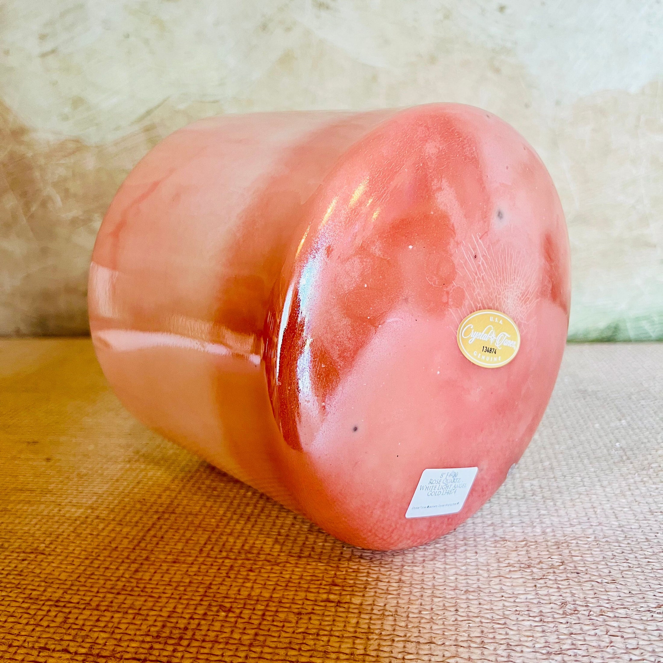 Pink cylindrical Crystal Sound Bowl with a Crystal Tones label on a textured surface