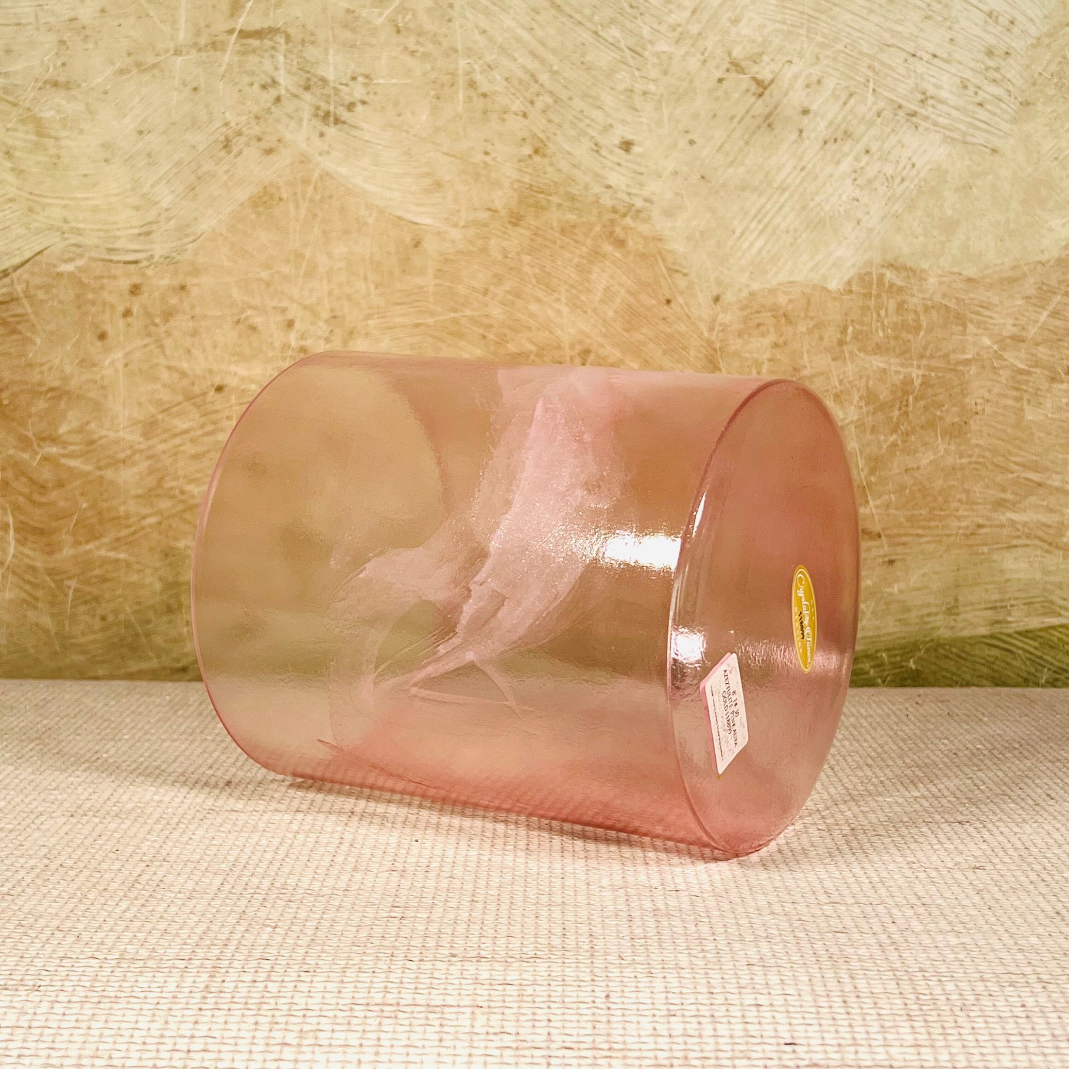 Clear pink crystal sound bowl with a Crystal Tones label on a textured surface