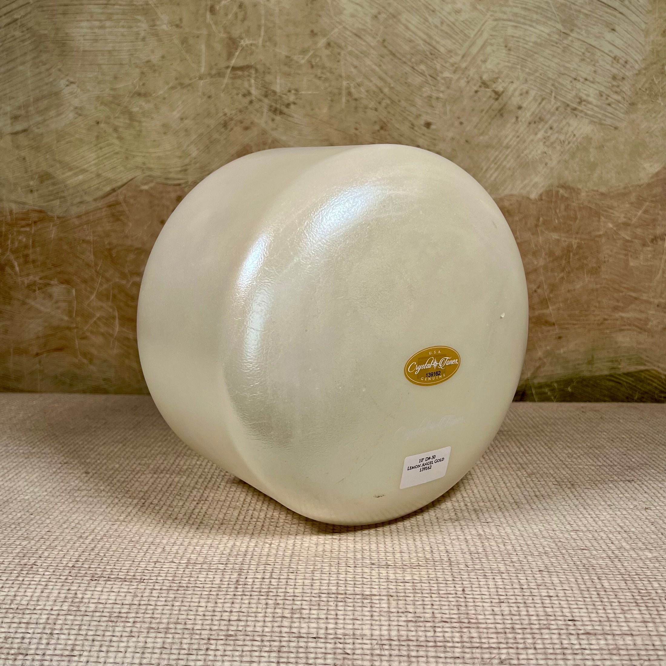 White crystal sound bowl with a gold Crystal Tones label on a textured surface