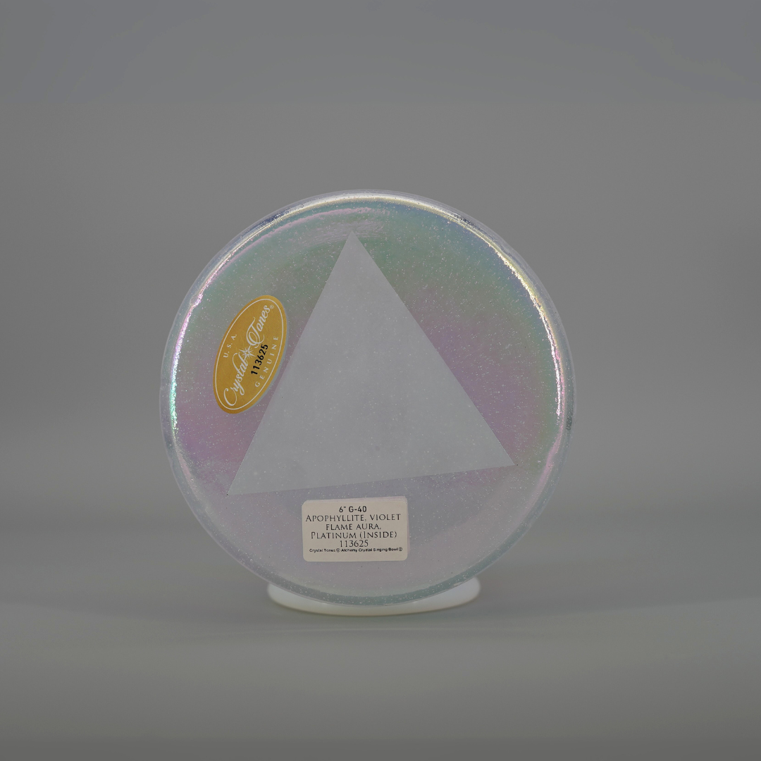 Round, iridescent crystal sound bowl with a triangle cutout on a gray background