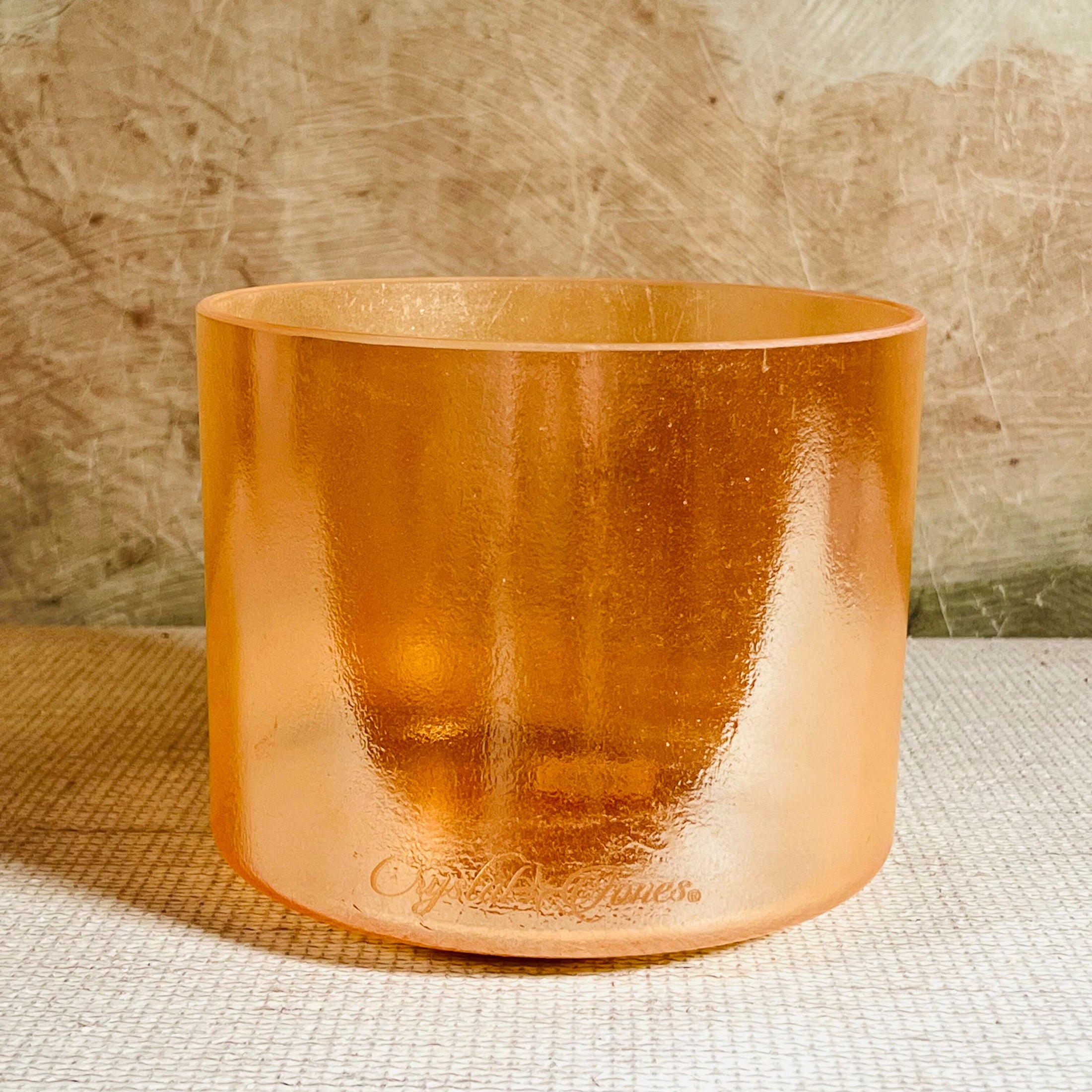 Copper-colored crystal sound bowl with 'Crystal Tones' branding on a textured surface.