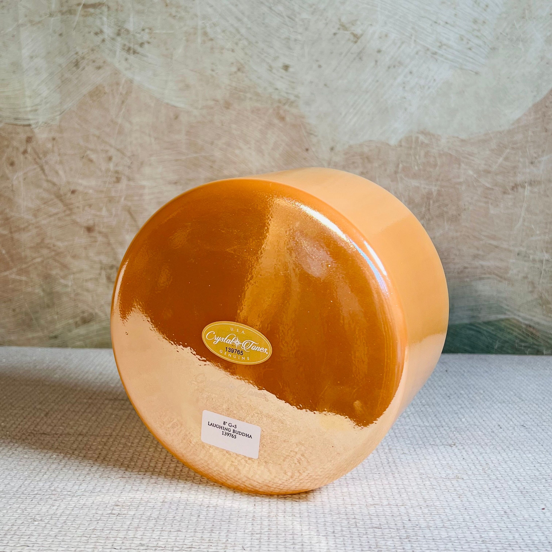 Round orange crystal sound bowl with a label on a textured surface