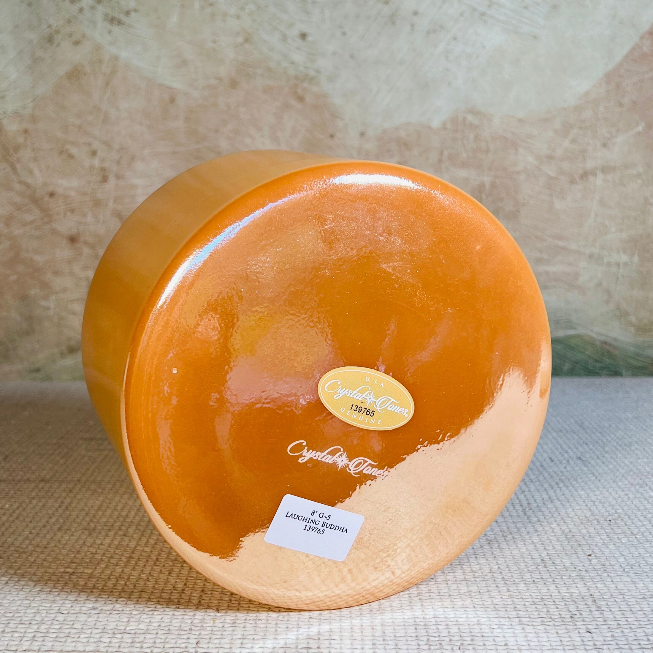 Round orange crystal sound bowl with a crystal tones label on a textured surface