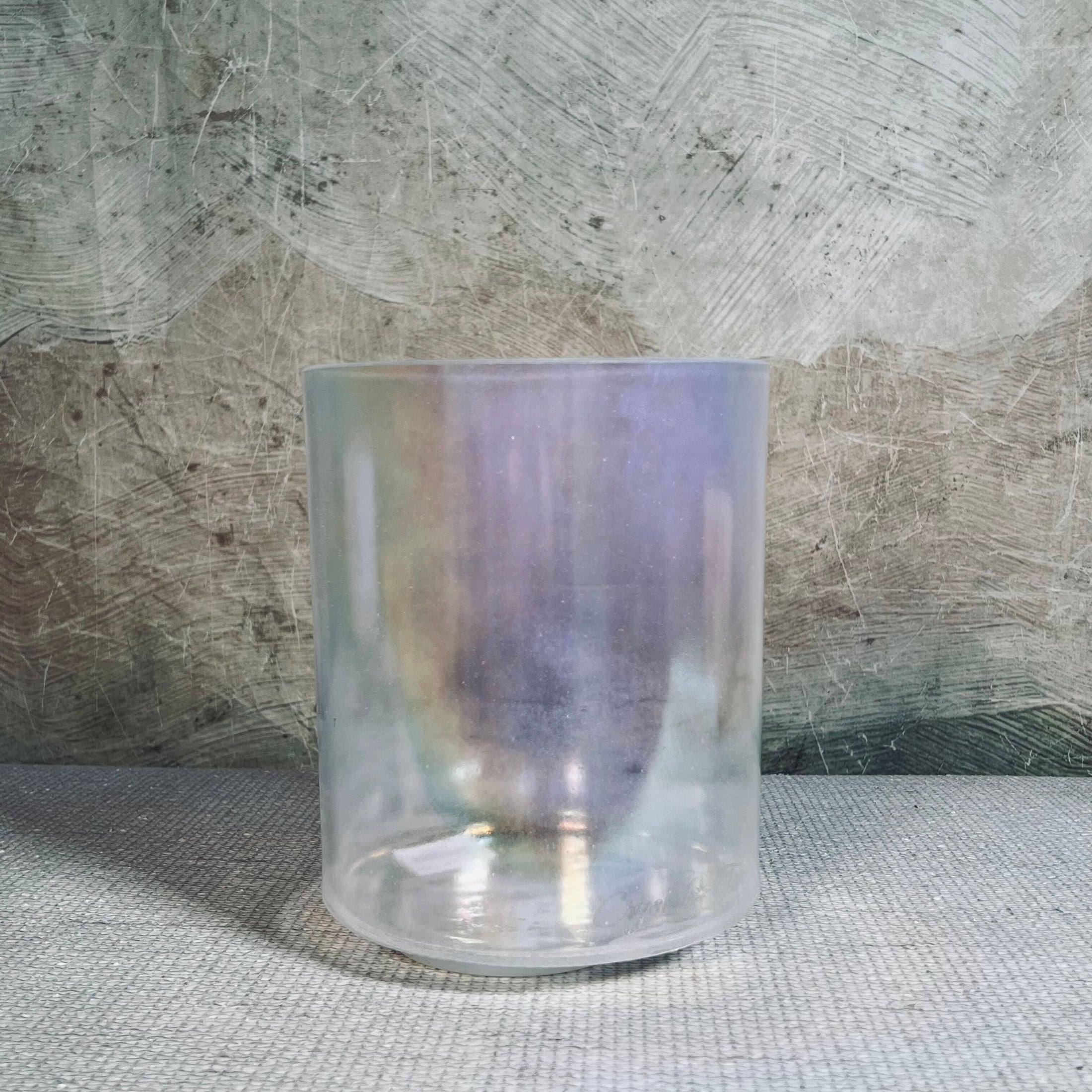 Iridescent crystal sound bowl on a textured surface