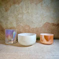 Load image into Gallery viewer, Three crystal sound bowls with different finishes on a textured surface.
