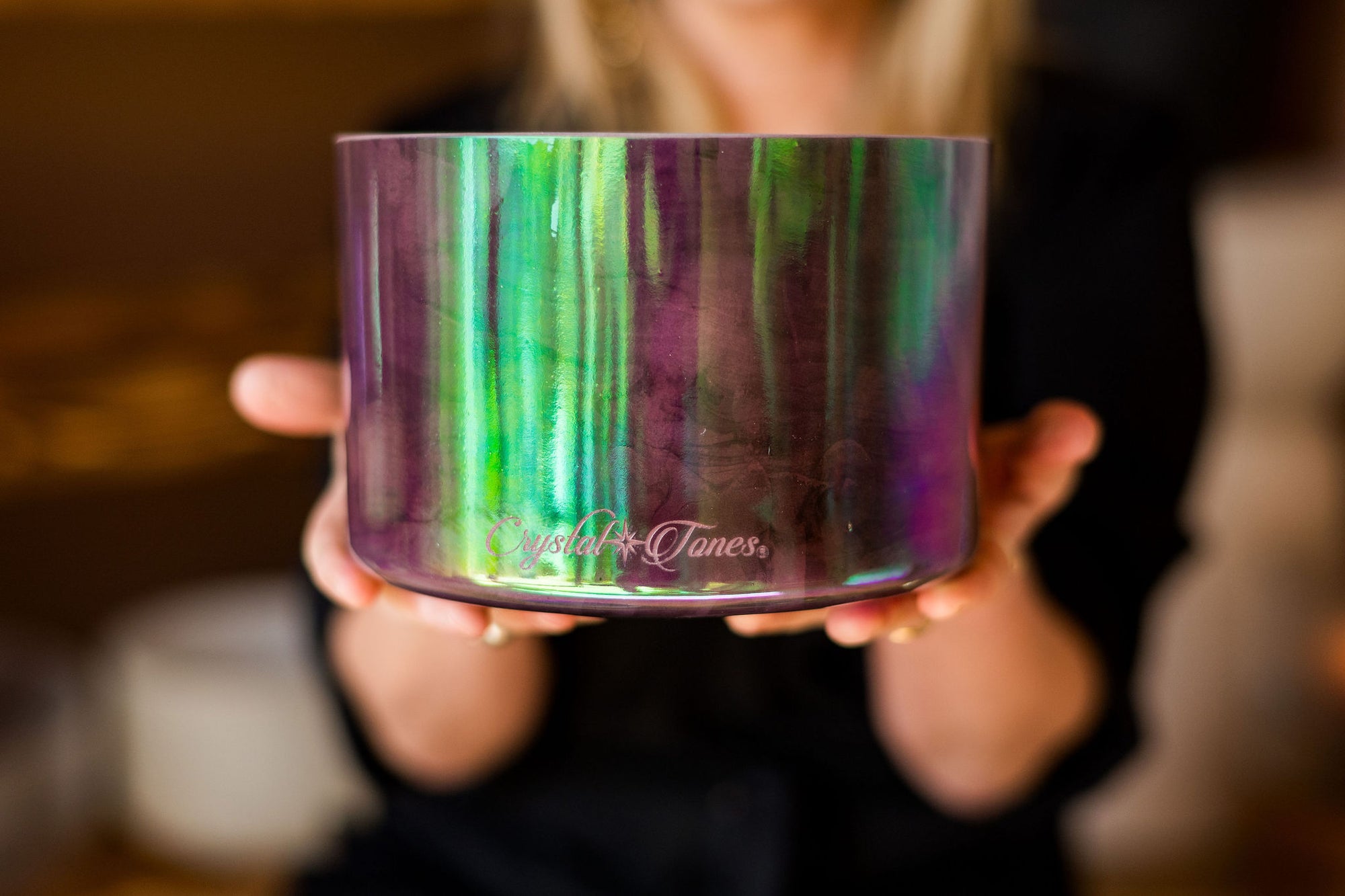 Person holding a colorful Crystal Sound Bowl with 'Crystal Tones' branding.