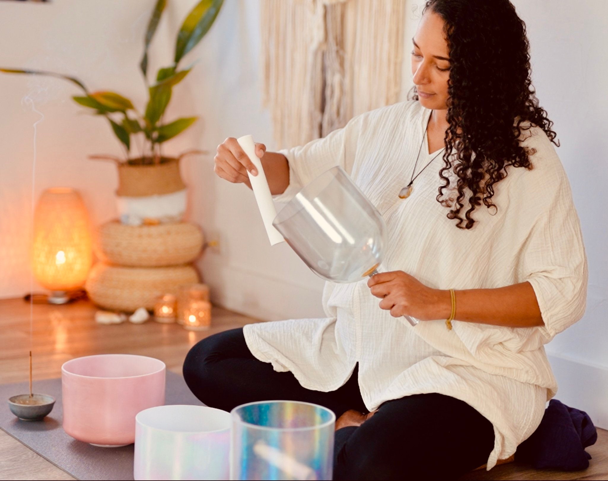 Woman - Casey - sitting on the floor with a clear glass container in a sound temple.