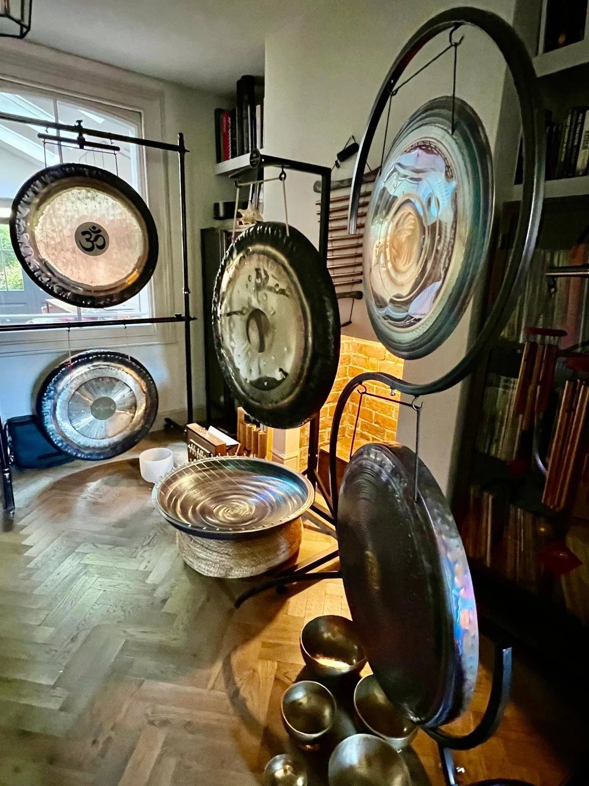 Collection of gongs on a wooden floor in a room with books and decor.